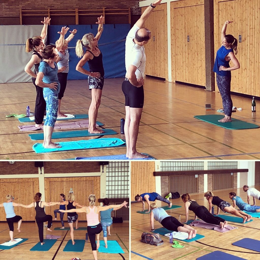 Yogagruppe übt Balancehaltungen in einer Turnhalle