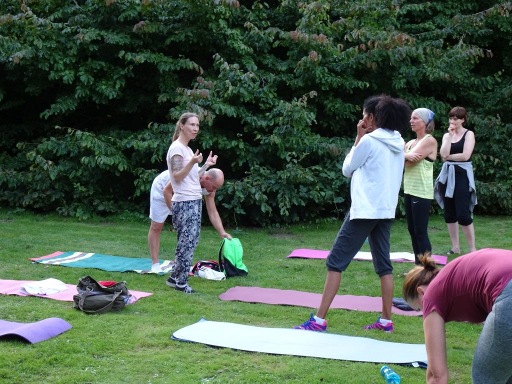 Yogagruppe übt im Freien auf einer Wiese im Park