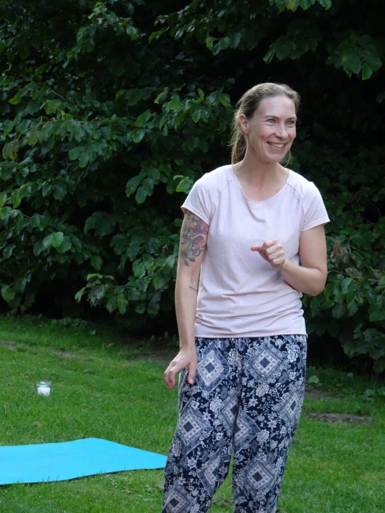 Bianka Polzius lächelnd auf einer Wiese bei einer Outdoor-Yogastunde