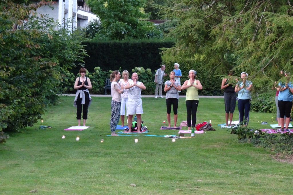 Yogagruppe übt im Freien auf einer Wiese im Park