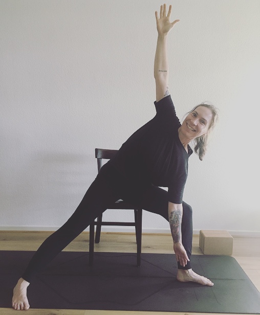 Bianka Polzius zeigt eine seitliche Dehnung mit Stuhl als Hilfsmittel – Yoga für Senioren