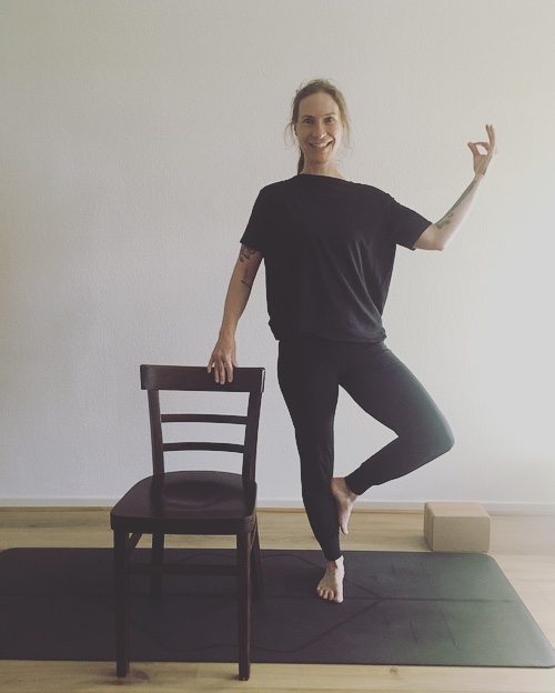 Bianka Polzius zeigt die Baumhaltung mit Stuhl als Stütze – Yoga für Senioren