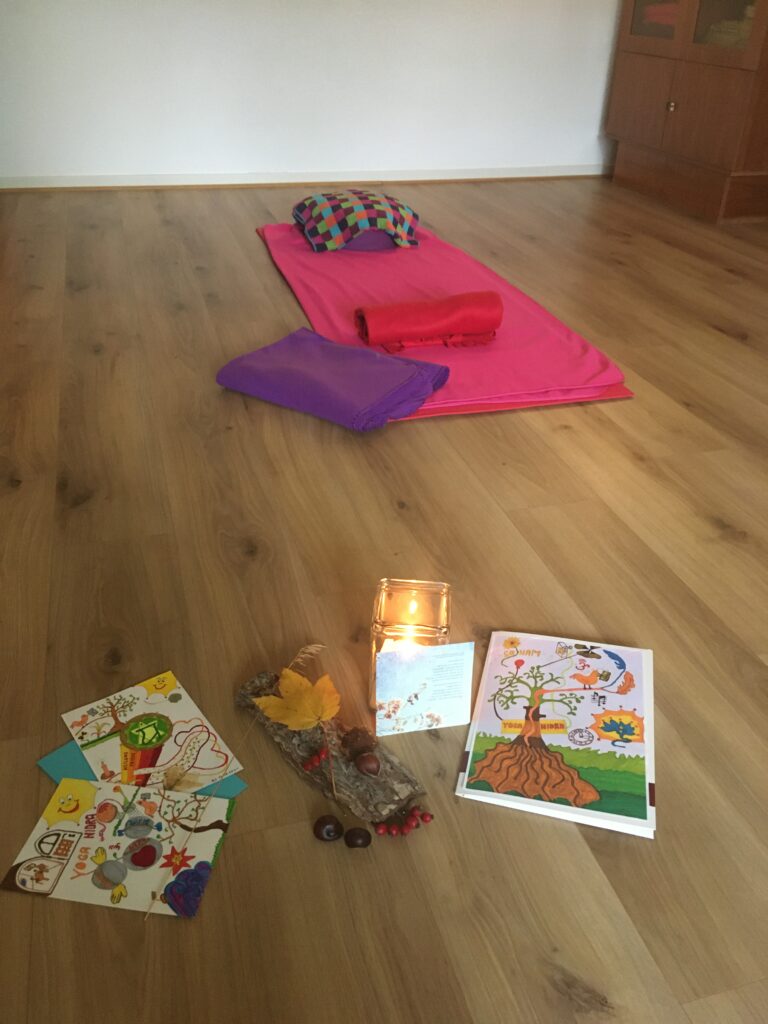 Vorbereiteter Yoga-Nidra-Raum mit Matten, Kissen, Kerze und Bildern
