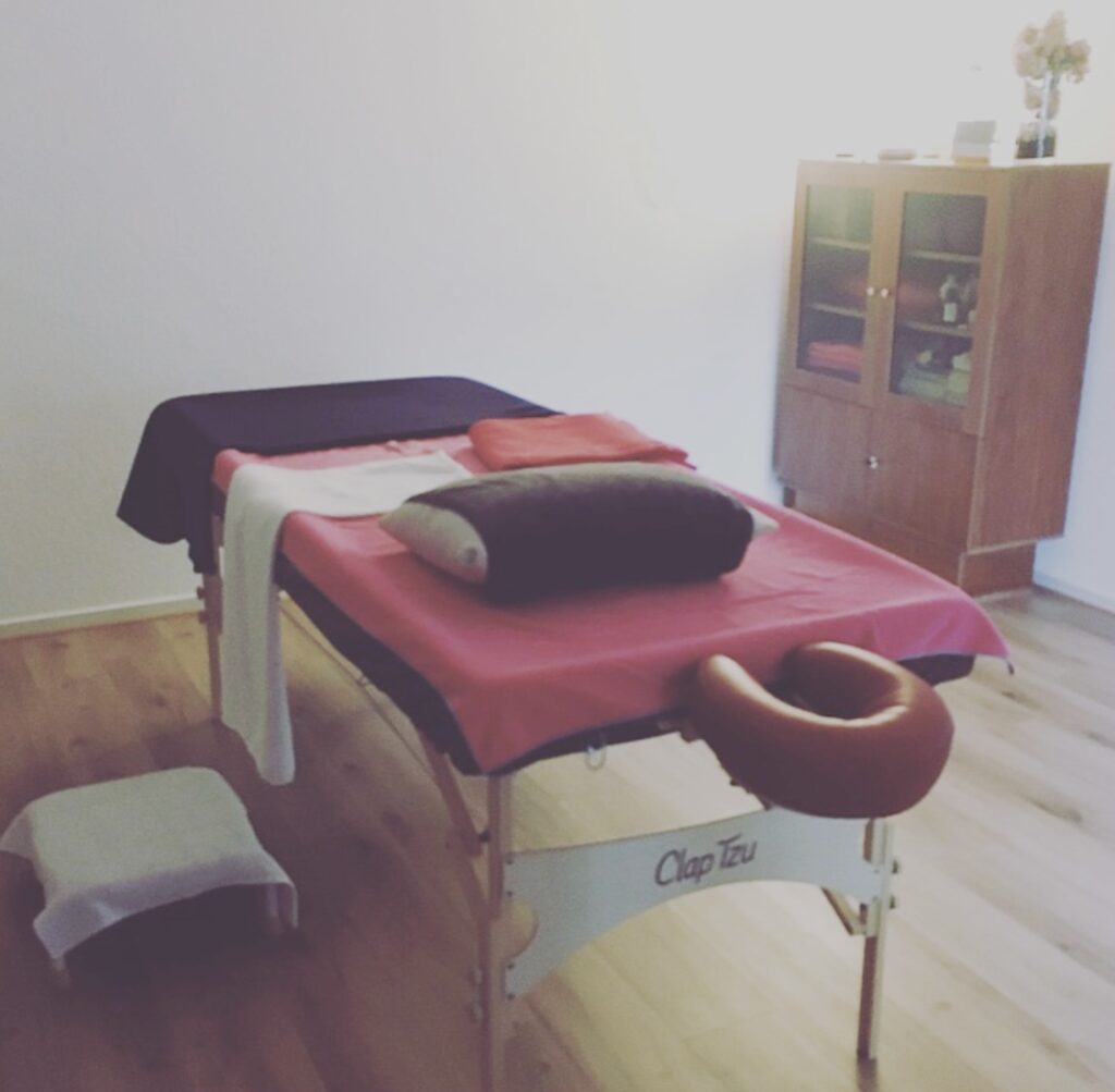 Massageliege mit Kissen in einem hellen Behandlungsraum