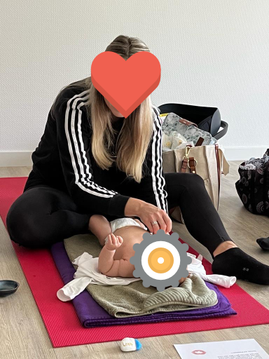 Mutter massiert ihr Baby auf einer Matte im Babymassage-Kurs